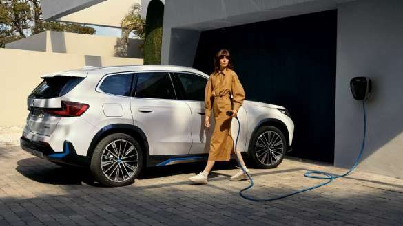 BMW iX1 U11 BEV 2022 Mineralweiß metallic ¾ Seitenansicht Garageneinfahrt parkend